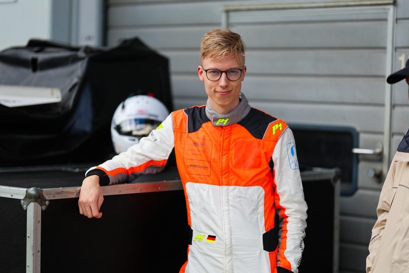 Leon Erger in his race suit in the paddock, helmet at his side