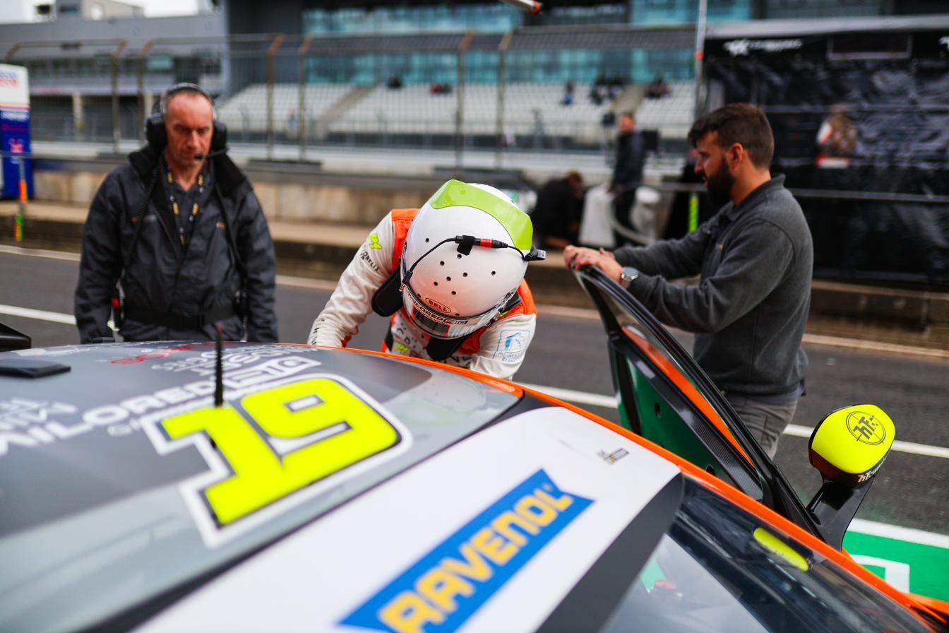 Climbing into the car in the pit lane during a driver change